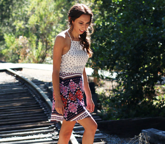 girl walking across train tracks wearing a dress