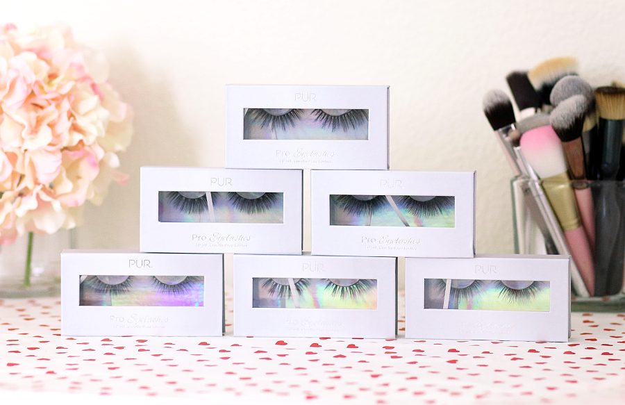 stack of false eyelashes in front of makeup brushes