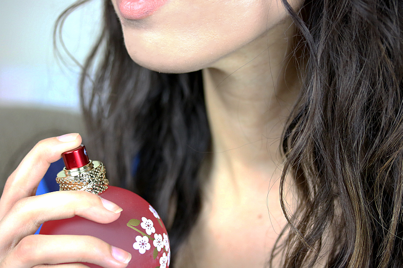 woman spraying perfume on her neck