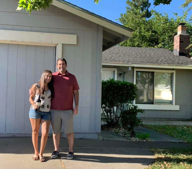 couple posing in front of house